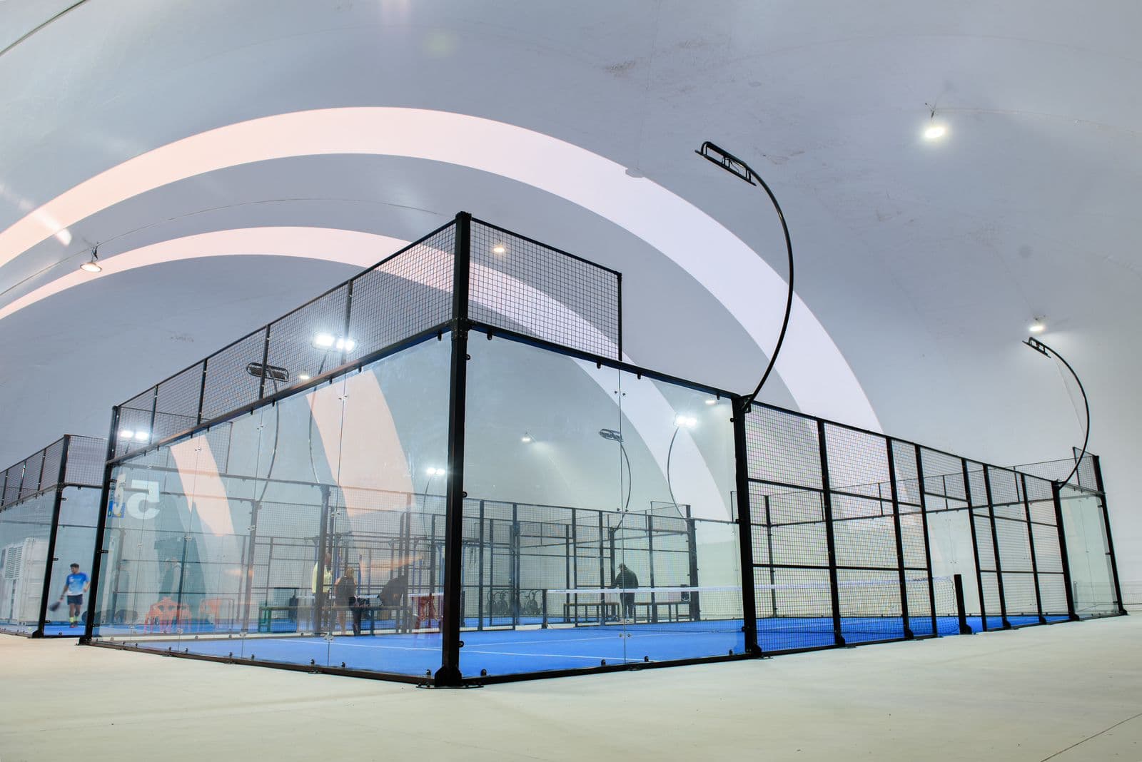 Interior de un domo Aerodomo con canchas de pádel y arco curvo característico